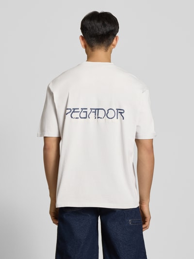 Männermodel trägt Oversized T-Shirt mit 1/2-Arm Modell 'Zernez' von Pegador, Reine Baumwolle, Rundhalsausschnitt, Label-Detail, Rückenlänge 72 cm, Ganzkörperansicht Rückansicht.