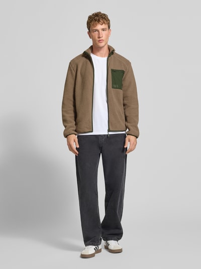 Männermodel trägt Regular Fit Teddyjacke mit Stehkragen Modell 'DALLAS' von ONLY in Braun mit grüner Brusttasche, Herren Teddy- / Webpelzjacke, Ganzkörperansicht von vorne.