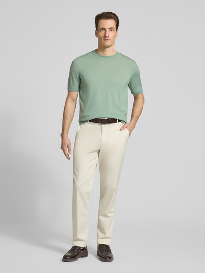 Männermodel trägt Regular Fit Strick-Shirt aus reiner Schurwolle Modell 'H-UMAURO' von BOSS in Grün, Rundhals, kurzarm, Ganzkörperansicht von vorne.