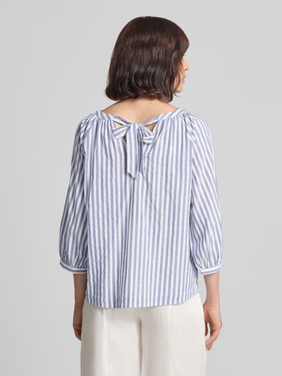 Frauenmodel trägt Loose Fit Kurzarmbluse aus Viskose-Baumwoll-Mix von s.Oliver RED LABEL, blaue und weiße Streifen, Ganzkörperansicht Rückansicht.