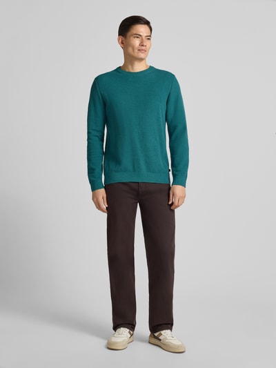 Męski model nosi Regular Fit Sweter z dzianiny z bawełny od Tom Tailor, efekt: jednolity kolor, dekolt okrągły, długi rękaw, zakończenia prążkowane, wykończenie: dzianina, materiał: czysta bawełna, kolor turkusowy, całkowity widok z przodu.
