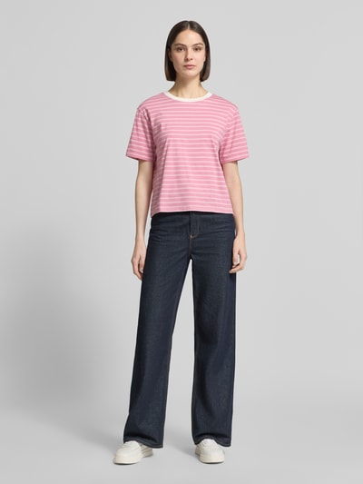 Modelka kobieca nosi Boxy Fit T-Shirt aus reiner Baumwolle od Tom Tailor Denim, różowe i białe paski, logo-patch, dekolt okrągły, krótki rękaw, fine rib, czysta bawełna, widok całej sylwetki z przodu.