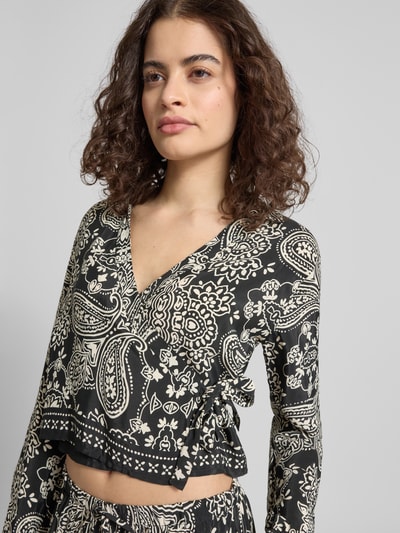 Frauenmodel trägt Shaped Fit Bluse aus reiner Viskose Modell 'LEMZA' von Only mit Florales-Allover-Muster, Wickeloptik, Bindegürtel, V-Ausschnitt, Langarm und Manschette, feine Webstruktur, Nahaufnahme Oberkörper.