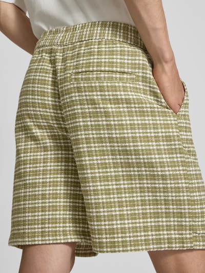 Männermodel trägt Shorts mit Strukturmuster Modell 'Kander' von Carhartt Work In Progress, grün-weiß kariert, Nahaufnahme Rückansicht