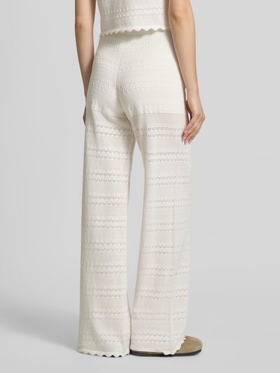 Frauenmodel trägt Strickhose mit Eingrifftaschen Modell 'Aurea' von OH APRIL aus cremefarbenem Baumwoll-Mix, Flared Fit, Ganzkörperansicht Rückansicht.