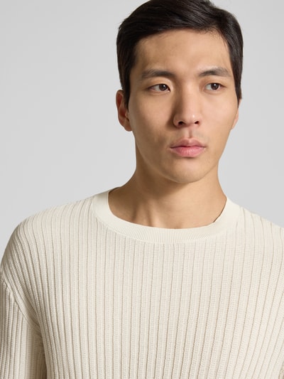 Männermodel trägt Slim Fit Pullover in Strick-Optik von ARMANI EXCHANGE in Creme, reine Baumwolle, Rundhalsausschnitt, Nahaufnahme Oberkörper.