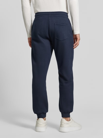 Männermodel trägt Straight Fit Jogginghose aus Baumwoll-Mix von MCNEAL in Dunkelblau mit elastischen Abschlüssen und Eingrifftaschen, Ganzkörperansicht Rückansicht.