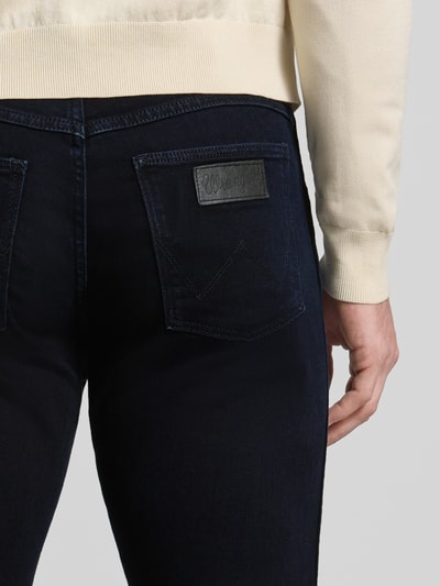 Männermodel trägt Straight Fit Jeans im 5-Pocket-Design Modell 'Greensboro' von Wrangler, dunkler Baumwoll-Mix, Detailaufnahme Rückansicht.