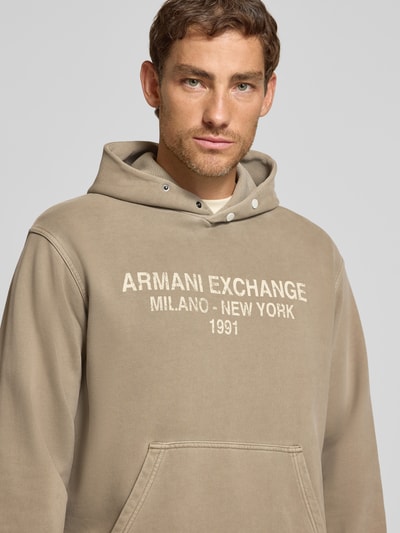 Männermodel trägt hoodie met labelprint van Armani Exchange, puur katoen, los model, capuchon, kangoeroezak, elastische boordjes, nahaufnahme oberkörper.
