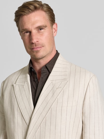 Männermodel trägt Relaxed Fit Sakko aus Leinen-Bauwoll-Mix Modell 'MALIK' von Selected Homme, hellbeige mit feinen Streifen, Nahaufnahme Oberkörper. Herren Sakko von Selected Homme.