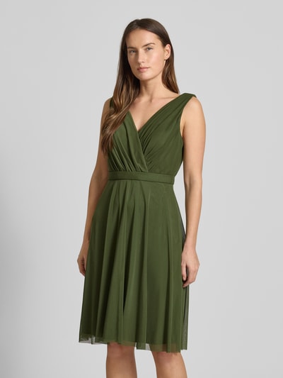 Vrouwenmodel draagt Cocktailkleid mit V-Ausschnitt van TROYDEN COLLECTION in olijfgroen met tailleband, plooien en ondoorzichtig onderjurk, volledig lichaamsaanzicht van voren.