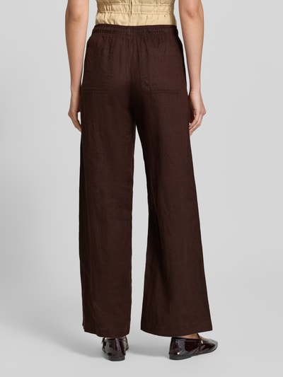 Frauenmodel trägt Leinenhose mit elastischem Bund Modell 'Mileni resort' von OPUS in Dunkelbraun, Wide-Leg-Fit, Ganzkörperansicht Rückansicht, französische Eingrifftaschen, Gesäßtaschen, reines Leinen, Bundweite 38 cm, Innenbeinlänge 80 cm bei Größe 36.
