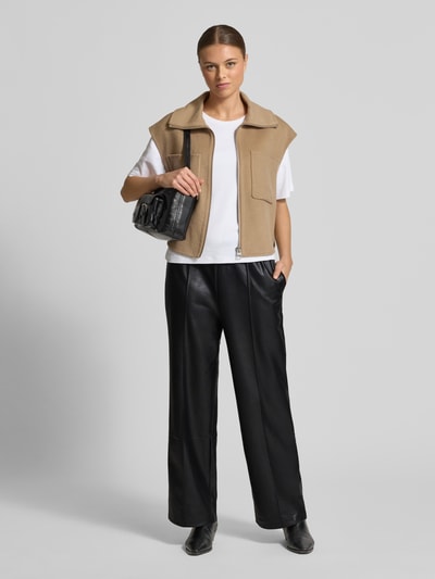 Kobiece modelka nosi Straight Fit Stoffhose in Leder-Optik od zero, czarne spodnie materiałowe z kantami, elastyczny pas z tunelem, materiał skóropodobny, szerokość w rozmiarze 36: 37 cm, długość wewnętrzna nogawki 74 cm, widok całej sylwetki z przodu.