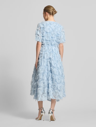 Frauenmodel trägt Cocktailkleid mit Fransen Modell 'PAZYLLA' von YAS in hellblau, A-Linie, strukturierte Oberfläche, Ganzkörperansicht Rückansicht.