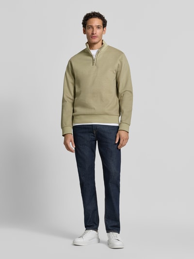 Männermodel trägt Regular Fit Troyer aus reiner Baumwolle Modell 'Sidney' von BOSS in Beige, kombiniert mit Jeans, Ganzkörperansicht von vorne, Herren Pullover von BOSS.