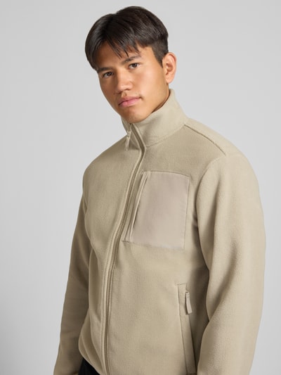 Männermodel trägt Fleecejacke mit Zweiwege-Reißverschluss Modell 'MASON' von JACK & JONES in Beige mit Stehkragen, Nahaufnahme Oberkörper.