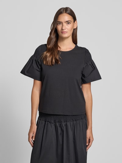 Frauenmodel trägt Regular Fit T-Shirt mit Smok-Detail von Comma, Damen T-Shirt aus reiner Baumwolle, ausgestellte Ärmel, Rundhalsausschnitt, Schwarz, Ganzkörperansicht von vorne.