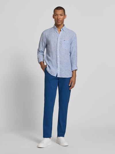Männermodel trägt Regular Fit Chino aus Baumwoll-Mix Modell "Denton" von Tommy Hilfiger in Blau, unifarben, Ganzkörperansicht von vorne.