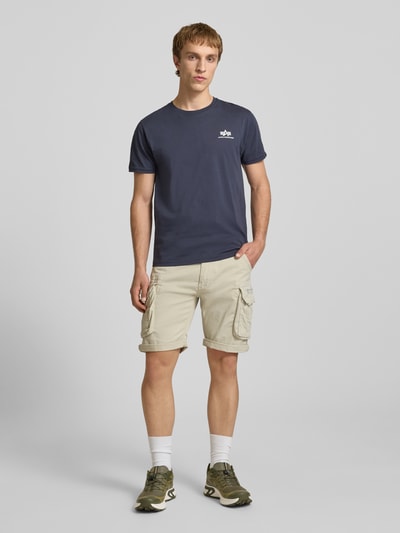 Męski model nosi Shorts mit Cargotaschen Modell 'CREW SHORT' od Alpha Industries, beżowy, bawełna z elastanem, krój regular fit, szerokość w rozmiarze 32: 44 cm, długość wewnętrzna nogawki w rozmiarze 32: 22 cm, cała sylwetka z przodu.