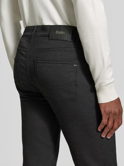 Männermodel trägt Stoffhose aus Baumwoll-Mix mit Viskose-Anteil Modell 'Cadiz' von Brax in Melange-Optik, 5-Pocket-Design, Detailaufnahme Rückansicht.