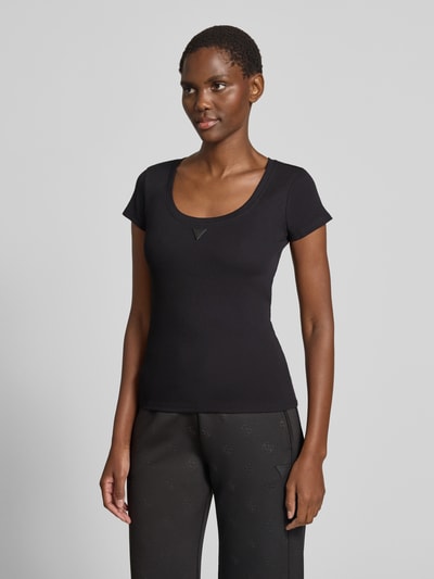 Frauenmodel trägt Slim Fit T-Shirt mit Logo-Applikation von Guess aus schwarzem Baumwoll-Mix, Rundhalsausschnitt, Ganzkörperansicht von vorne. Rückenlänge bei Größe S: 52 cm.
