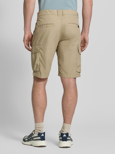 Männermodel draagt Bermudas met cargozakken van camel active in beige, puur katoen, regular fit, steekzakken, labeldetail, binnenbeenlengte maat 32: 26 cm, bandwijdte maat 32: 44 cm. Ganzkörperansicht Rückansicht.