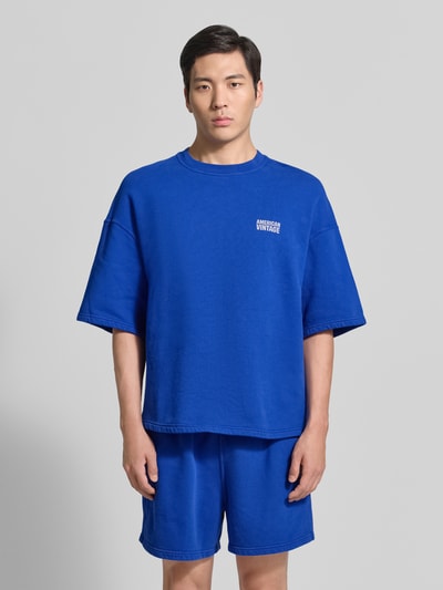 Männermodel trägt Herren T-Shirt mit Logo Modell 'PLIZZY' von American Vintage in Blau, Reine Baumwolle, Relaxed-Fit, Rundhalsausschnitt, Ganzkörperansicht von vorne.