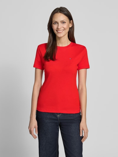 Kobiece modelka nosi Slim Fit T-Shirt aus reiner Baumwolle von Tommy Hilfiger, czerwony jednolity jersey, logo, okrągły dekolt, krótkie rękawy, ujęcie całej sylwetki z przodu.