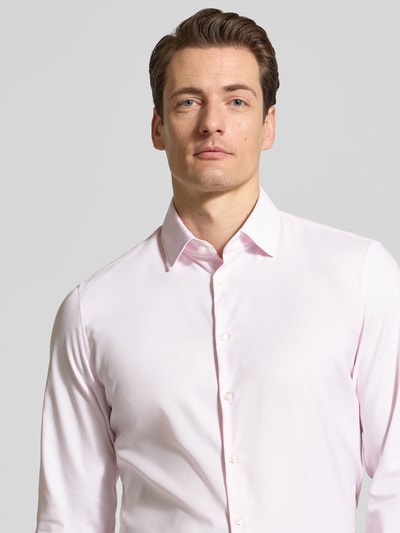 Męski model nosi Slim Fit Business-Hemd mit Kentkragen von Jake*s, mieszanka materiałów z dodatkiem streczu, listwa guzikowa, długość tyłu 71 cm, szerokość w rozmiarze 45 cm, długość rękawów 65 cm, jasnoróżowy kolor, gładka faktura, prosty krój, krój slim fit; zbliżenie na górną część ciała.