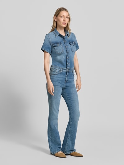 Frauenmodel trägt Flared Denim-Jumpsuit Modell 'KIMMY' von Mustang aus Baumwoll-Elasthan-Mix mit Umlegekragen, Knopfleiste, Brusttaschen, Label-Detail, in hellblauer Denim-Optik, Ganzkörperansicht von vorne. Rückenlänge bei Größe S: 53 cm, Brustweite: 46 cm, Ärmellänge: 20 cm, Gesamtlänge: 165 cm, Innenbeinlänge: 83 cm.