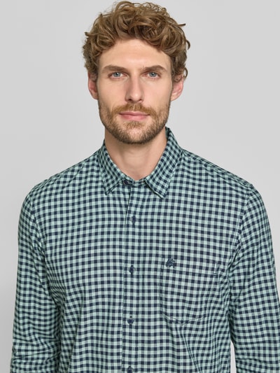 Męski model nosi Regular Fit Freizeithemd mit Button-Down-Kragen od LERROS, mieszanka bawełny, wzór na całej powierzchni, Brustasza, wyhaftowane logo, Długość tyłu w rozmiarze M 75 cm, Szerokość w rozmiarze M 43 cm, Długość rękawów w rozmiarze M 70 cm, zbliżenie na górną część ciała.