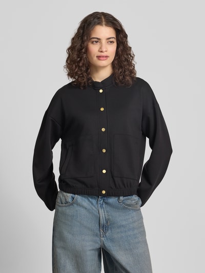 Männermodel trägt Regular Fit Bomberjacke mit Viskose-Anteil Modell 'TALIA' von Pieces, czarna, jednokolorowa, krój regular fit, stehkraag, długi rękaw, elastyczny dół, boczne kieszenie, materiał sweat, Ganzkörperansicht von vorne.