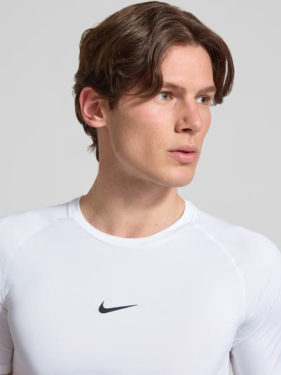 Männermodel trägt Herren T-Shirt mit Logo-Print und Rundhalsausschnitt von NIKE TRAINING, Slim Fit, weiße Farbe, Nahaufnahme Oberkörper.