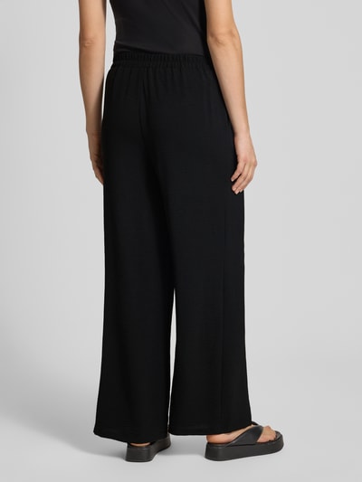 Frauenmodel trägt Weite Hose in Crêpe-Verarbeitung Modell 'TIFFANY' von Pieces, Optik: Unifarben, Passform: Wide Leg, Bundabschluss: elastisch, seitliche Eingrifftaschen, Materialverarbeitung: Crêpe, Ganzkörperansicht Rückansicht.