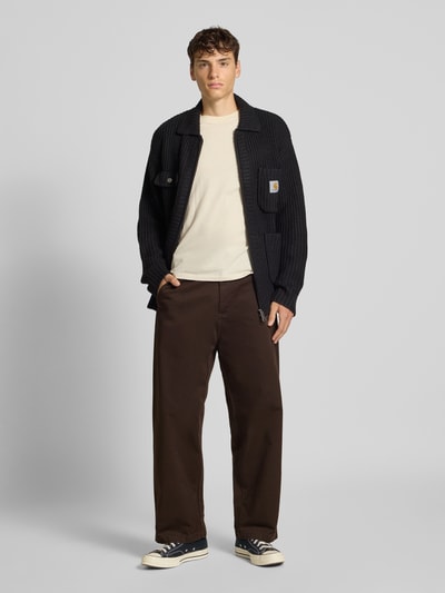 Männermodel trägt Wide Leg Hose mit Eingriff- und Gesäßtaschen Modell 'BRADY' von Carhartt Work In Progress aus brauner Baumwolle, Ganzkörperansicht von vorne.