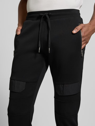 Männermodel trägt Slim Fit Sweatpants mit Gesäßtaschen von Antony Morato, schwarze Baumwoll-Mix Textur, Nahaufnahme Hüfte