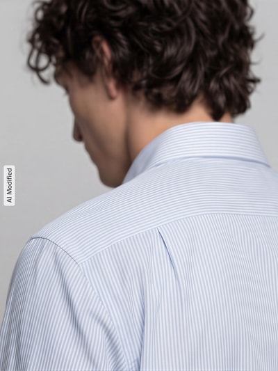 Männermodel trägt Regular Fit Businesshemd aus reiner Baumwolle Modell 'New Kent' von Seidensticker, feine hellblaue Streifen, Ganzkörperansicht Rückansicht, Herren Businesshemd von Seidensticker.