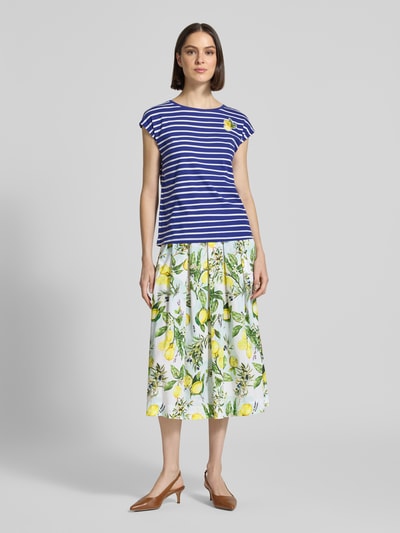 Frauenmodel trägt Midirock im Allover-Look von Marc Cain aus Reine Baumwolle, A-Linie, weiß mit gelb-grünem Muster, Ganzkörperansicht von vorne.