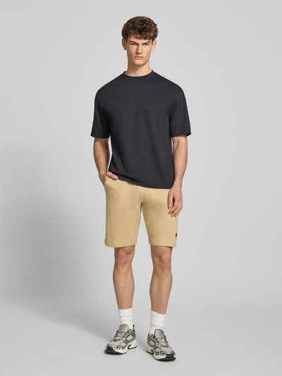 Mannenmodel draagt Straight Fit Shorts met logo-stitching model 'Fillip' van Blend in beige, puur katoen, structuurpatroon, steekzakken, achterzak, elastische band met tunnelkoord, bandwijdte maat M 39 cm, binnenbeenlengte maat M 26 cm, ganzebody aanzicht van voren.