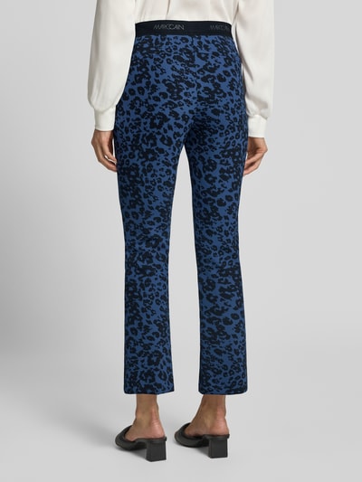 Frauenmodel trägt Flared Fit Leggings mit Allover-Animal-Print von Marc Cain in Blau und Schwarz, elastischer Bund, Logo-Detail, Ganzkörperansicht Rückansicht.