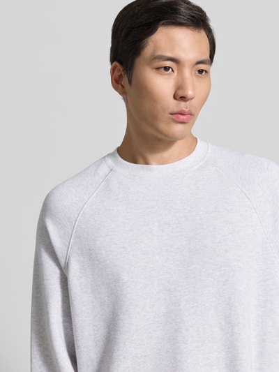 Männermodel trägt Sweatshirt mit Rundhalsausschnitt Modell 'ATUBAY' von American Vintage aus Baumwoll-Elasthan-Mix in Hellgrau, Nahaufnahme Oberkörper. Relaxed-Fit, Rückenlänge 67 cm, Ärmellänge 77 cm, Größe M/L.