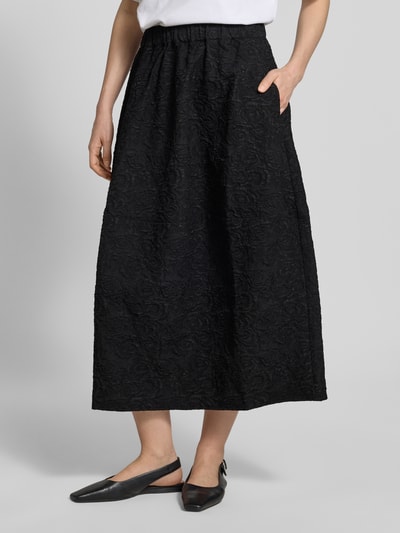 Vrouwenmodel draagt midirok in zwarte all-over look met A-lijn en elastische band, model 'ROSIE' van Copenhagen Muse, totale lengte, vooraanzicht