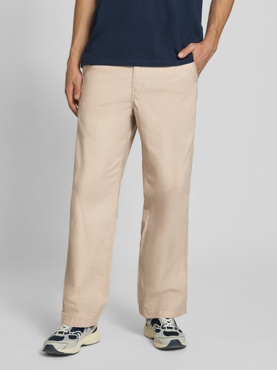 Männermodel trägt Wide Fit Hose aus reiner Baumwolle Modell 'Bill' von JACK & JONES in Beige, Eingriff- und Gesäßtaschen, Ganzkörperansicht von vorne.
