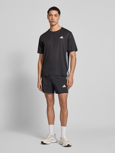 Männermodel trägt Regular Fit T-Shirt mit Logo-Print von adidas Training, Optik: Unifarben, Kontraststreifen, schnelltrocknend, Ganzkörperansicht von vorne.