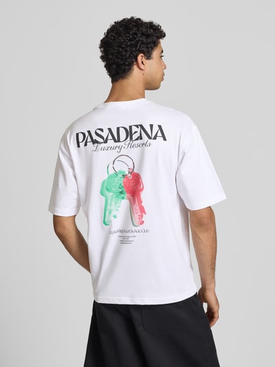 Männermodel trägt Boxy Fit T-Shirt aus reiner Baumwolle Modell 'FRED ESCAPE' von Only & Sons, weiß, Motiv-Print, Ganzkörperansicht Rückansicht