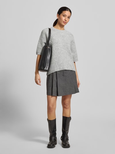 Modelka nosi Strickpullover mit gerippten Abschlüssen Modell 'ZOLLY' od American Vintage, jasnoszary melanż, luźny krój, półrękawy, widok całej sylwetki z przodu.