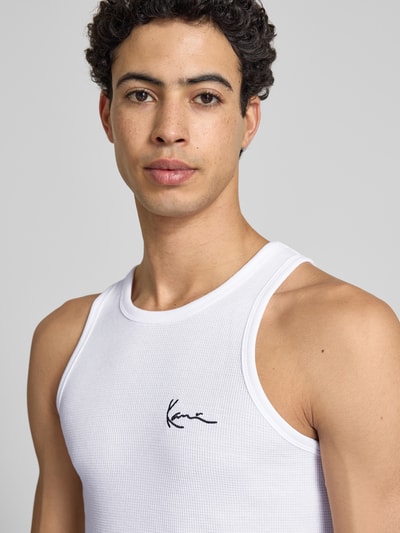 Männermodel trägt Slim Fit Top mit Logo-Stitching von KARL KANI in Weiß aus Baumwoll-Mix, Rundhalsausschnitt, Nahaufnahme Oberkörper. Rückenlänge bei Größe M: 68 cm.