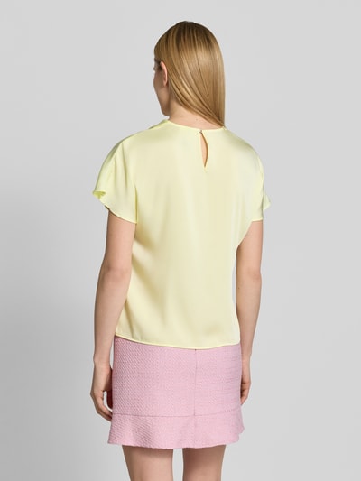 Modelka nosi Blusenshirt aus Satin mit Umlegekragen od Marc Cain, jasnożółty satynowy materiał, krój regular fit, widok całej sylwetki z tyłu.