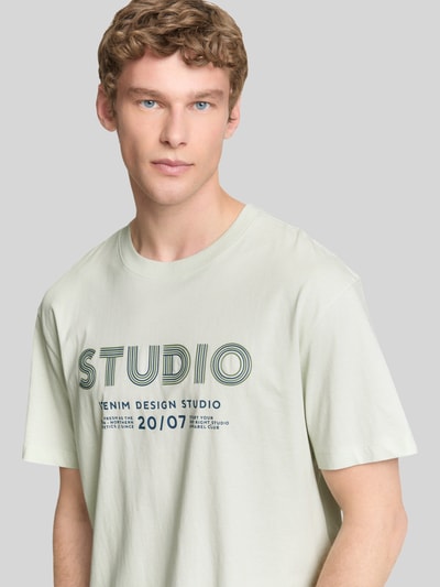 Männermodel trägt Relaxed Fit T-Shirt aus reiner Baumwolle von Tom Tailor Denim in Optik: Unifarben, Label-Print, Ganzkörperansicht von vorne