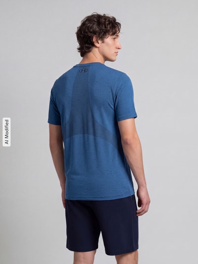 Mężczyznamodel nosi Regular Fit Sport-T-Shirt mit Logo-Print od Under Armour w niebieskim kolorze, strukturalna tkanina, widok całej sylwetki od tyłu, KI-modifiziertes Bild